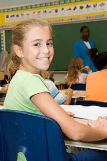 smiling fifth grade girl sitting at her desk