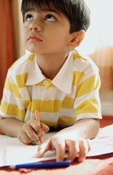 first grade boy at desk, looking up